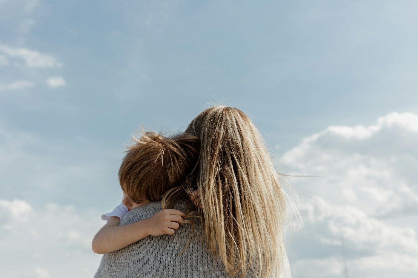 Une mère tenant son enfant contre un ciel nuageux